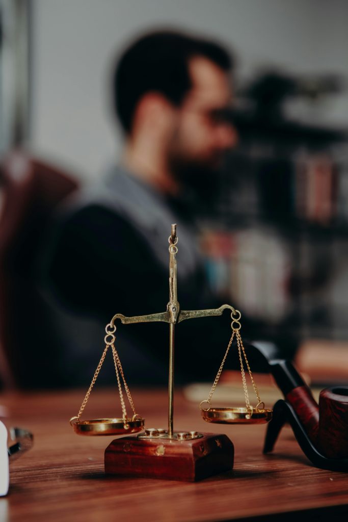 Close-up of justice scales and pipe on a lawyer's desk, emphasizing legal themes.